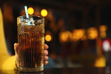 Photo of Woman with glass of refreshing cola at table indoors, closeup. Space for text