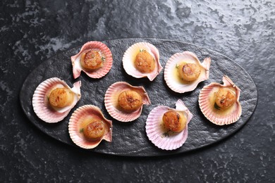 Photo of Delicious fried scallops in shells on black table, top view