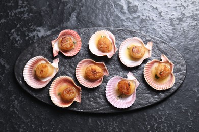 Delicious fried scallops in shells on black table, top view