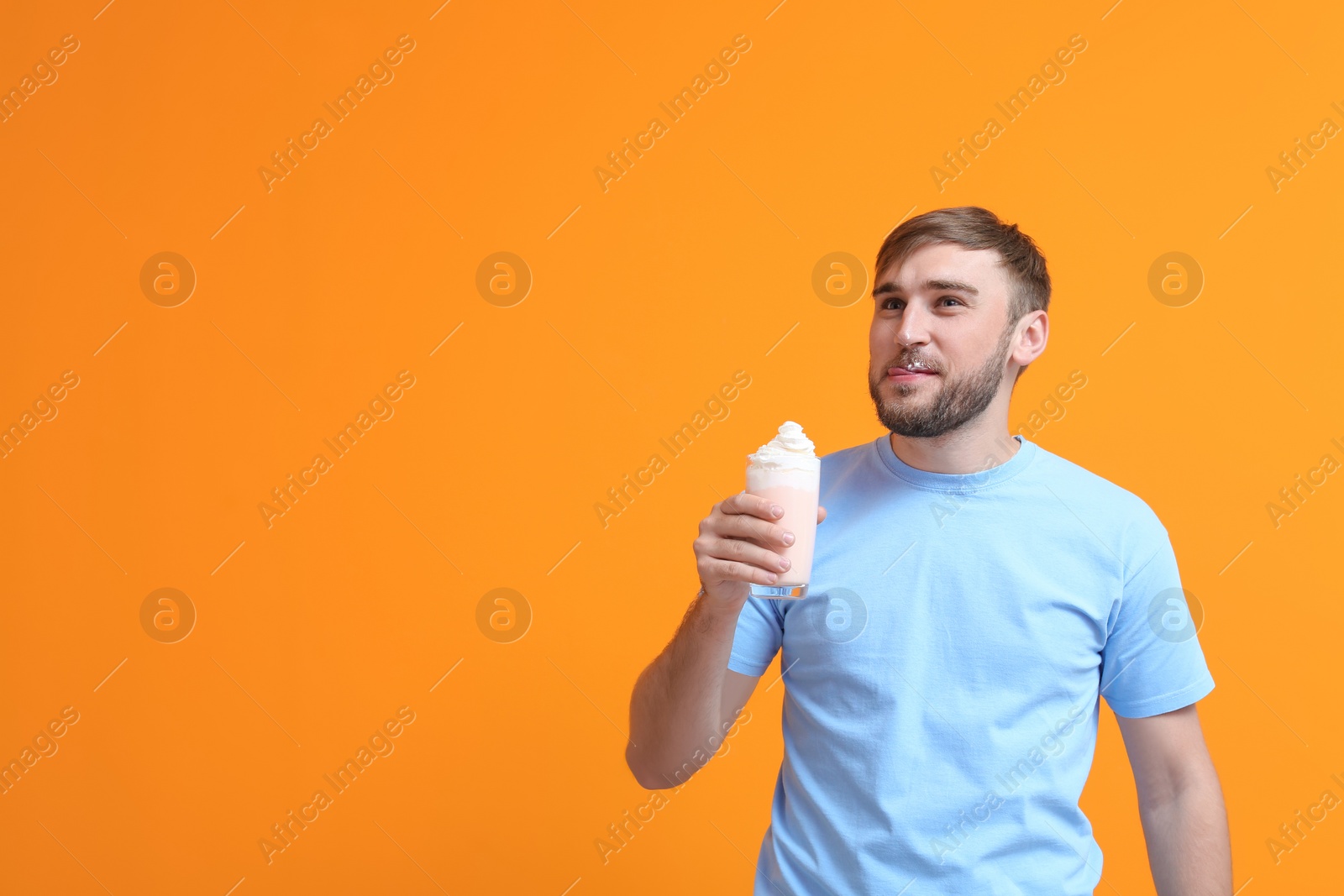 Photo of Young man with glass of delicious milk shake on color background