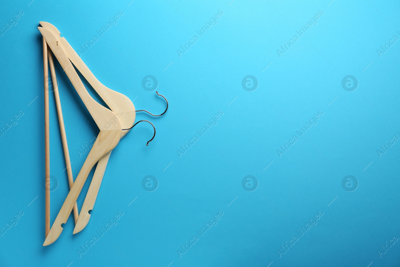 Photo of Wooden hangers on light blue background, top view. Space for text