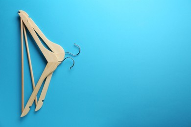 Photo of Wooden hangers on light blue background, top view. Space for text