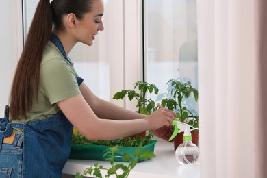 Happy woman planting seedling into pot near window indoors