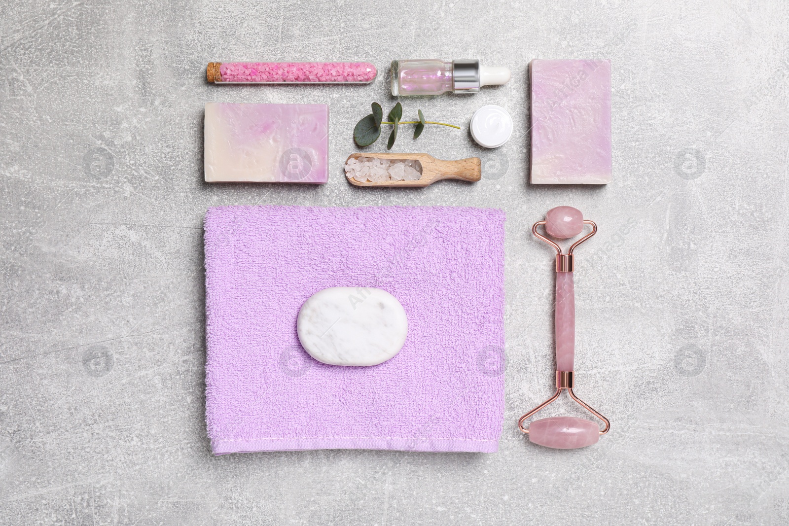 Photo of Flat lay composition with face roller and cosmetic products on light grey stone table