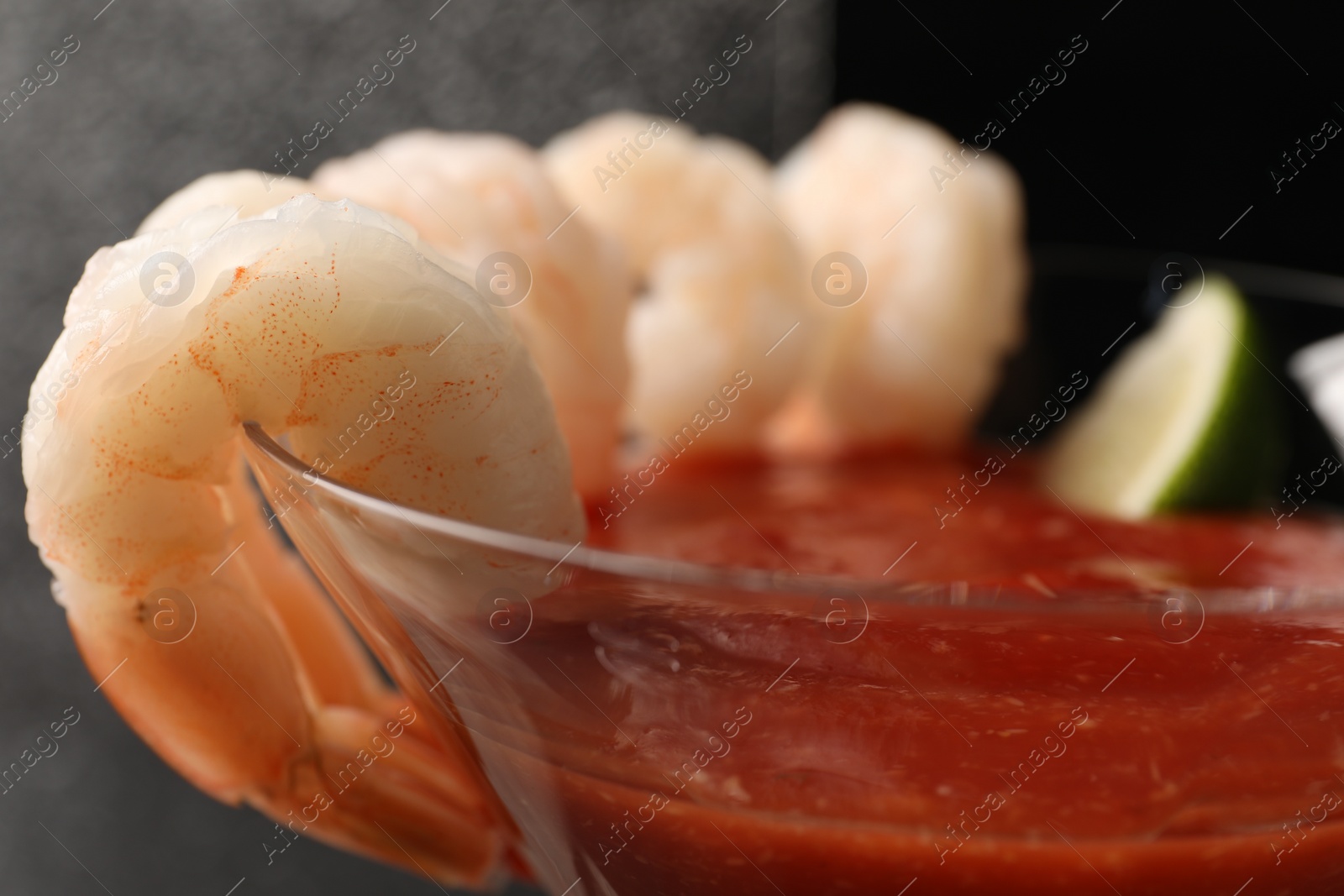 Photo of Tasty shrimp cocktail with sauce in glass on blurred background, closeup