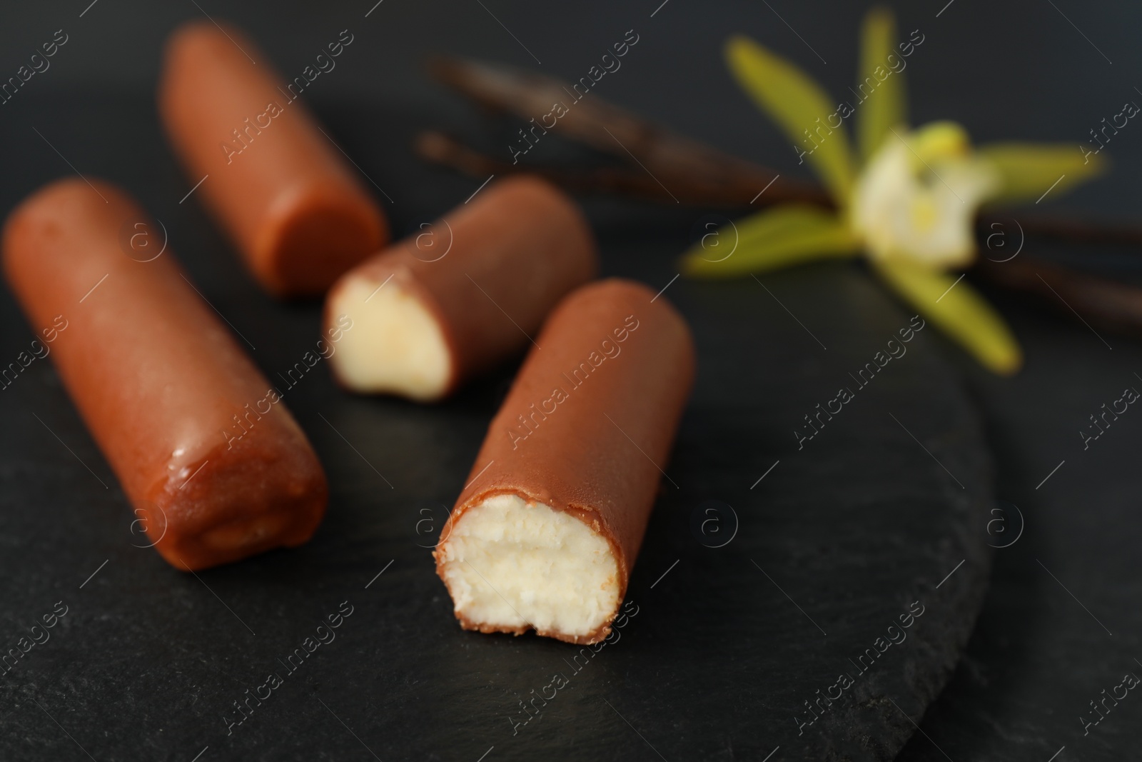 Photo of Glazed curd cheese bars on black table, closeup