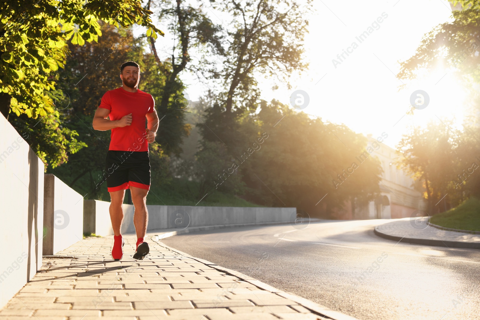 Photo of Happy man running outdoors on sunny day. Space for text