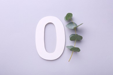 Paper number 0 and eucalyptus branch on light grey background, top view