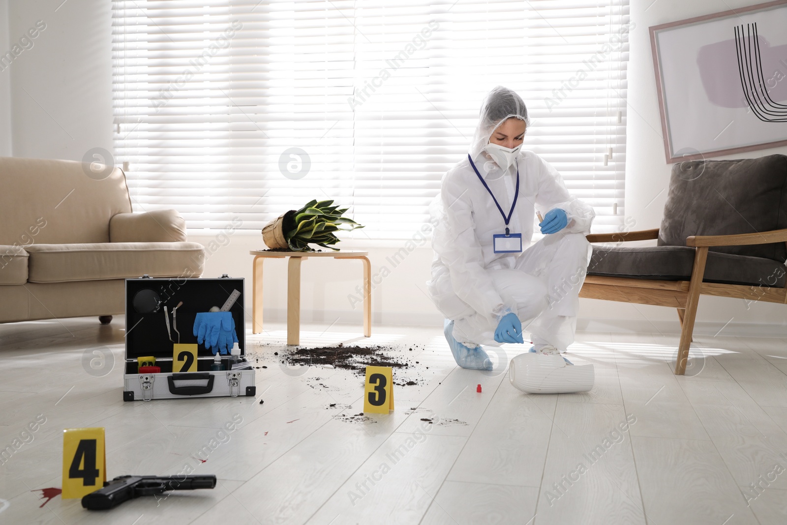 Photo of Investigator in protective suit working at crime scene indoors