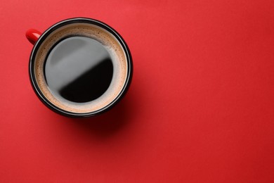 Fresh coffee in cup on red background, top view. Space for text