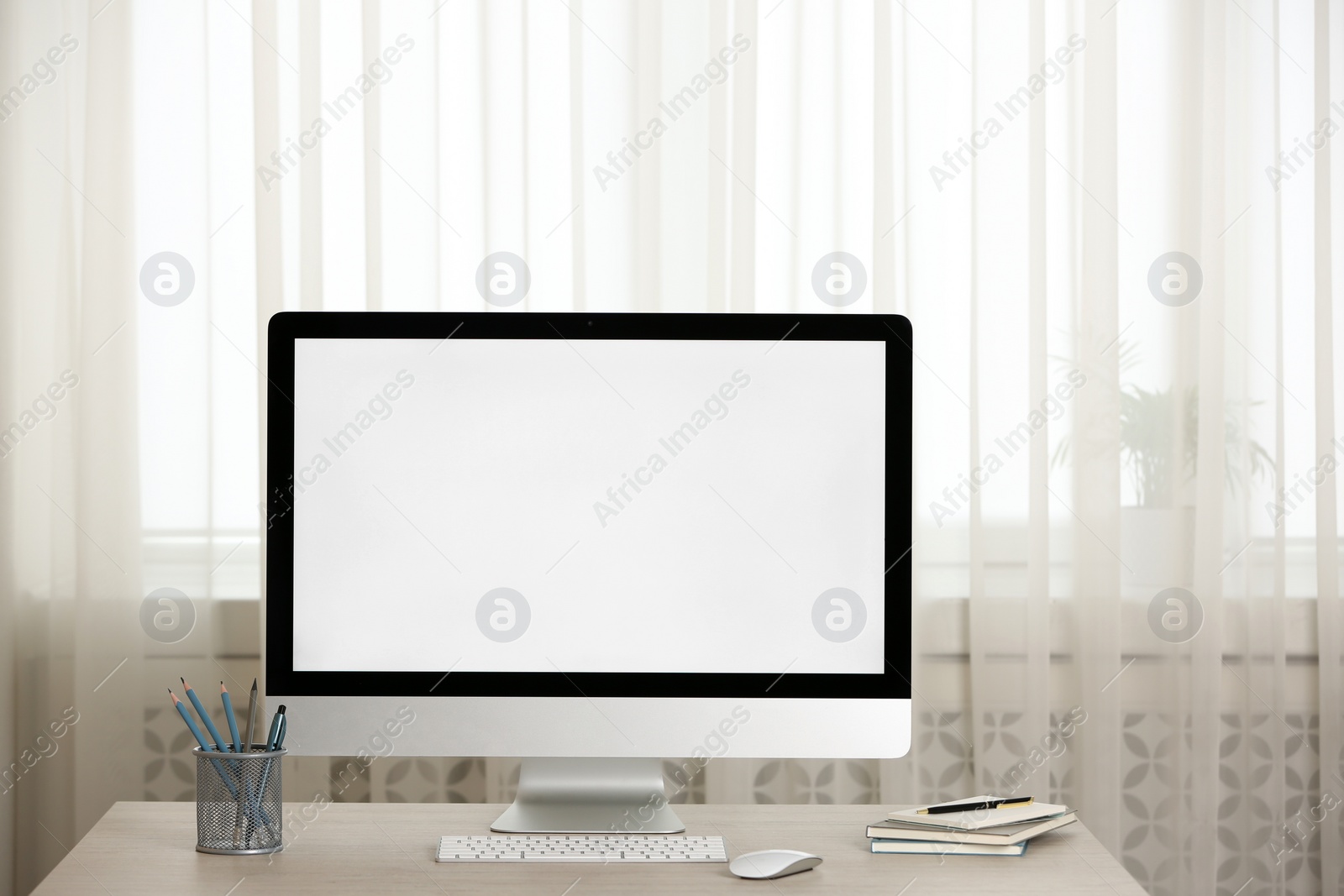 Photo of Modern computer with blank screen and stationery on table indoors. Space for design