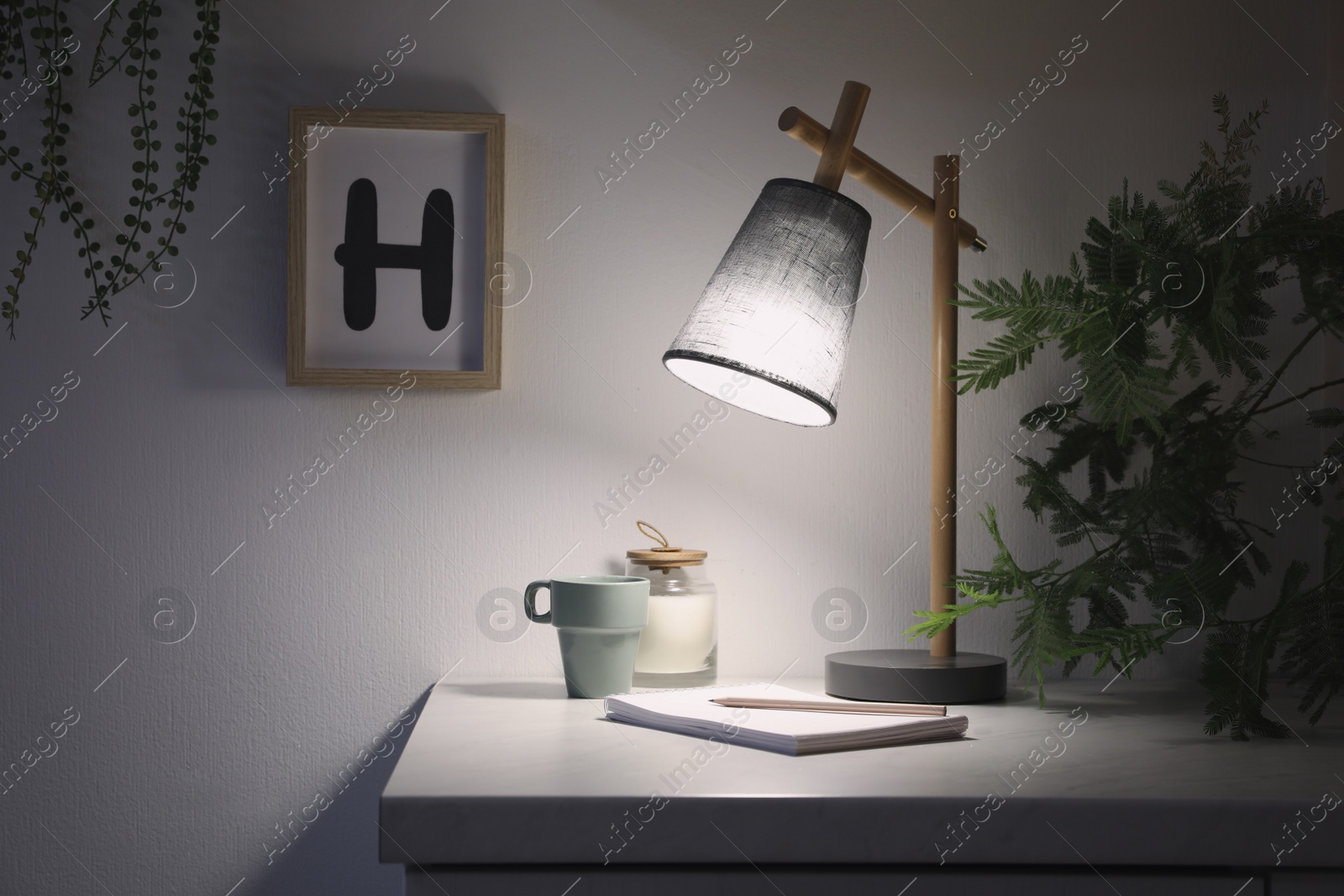Photo of Stylish lamp and decor on white cabinet in room. Interior element