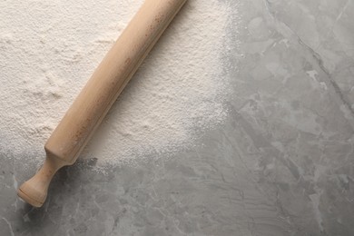 Pile of flour and rolling pin on grey marble table, top view. Space for text