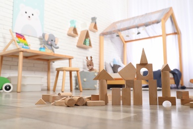 Photo of Wooden toy construction set on floor in playroom. Interior design