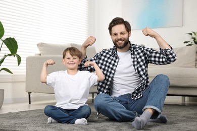 Happy dad and son sitting on carpet at home