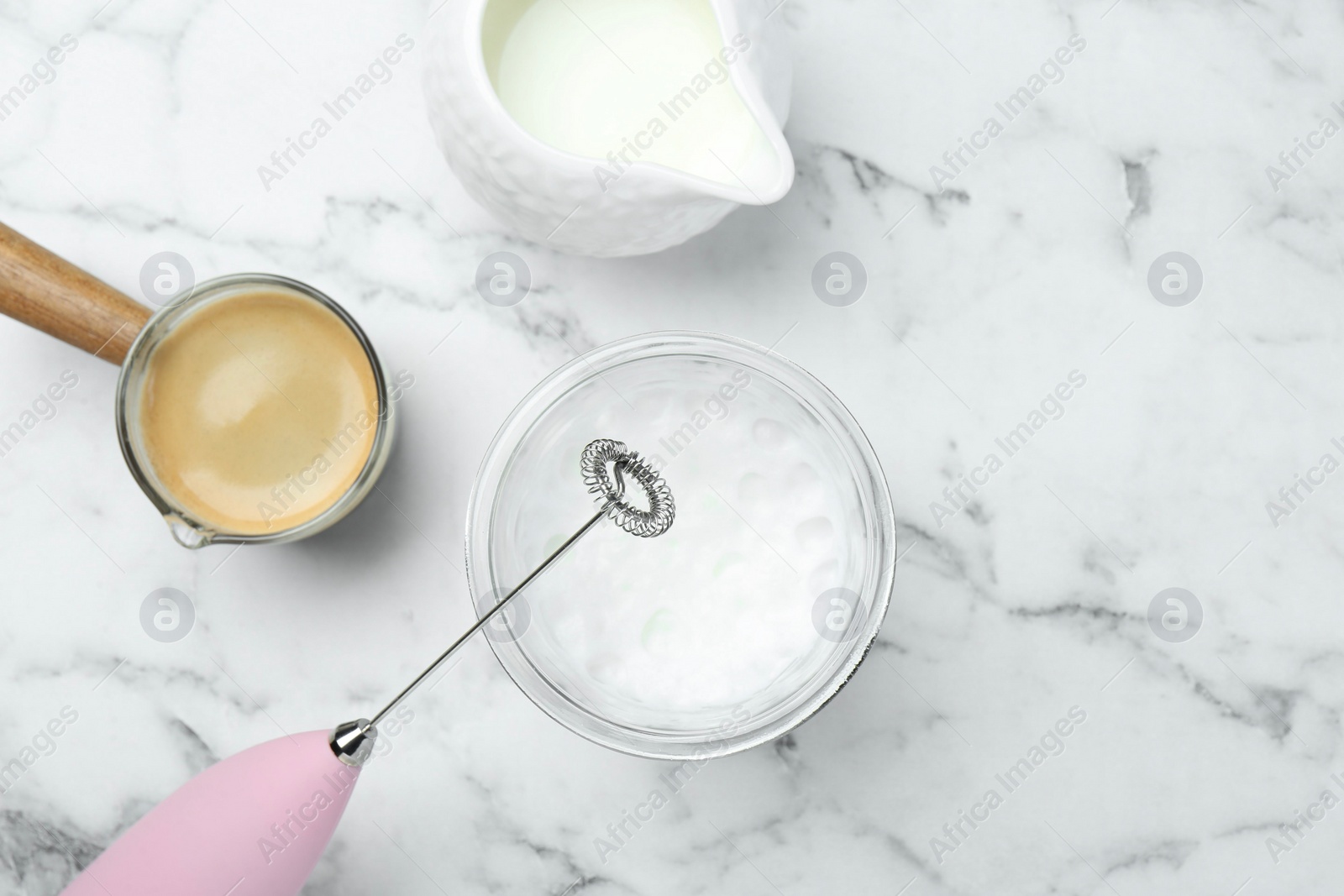 Photo of Flat lay composition with mini mixer (milk frother), whipped milk in glass and coffee at white marble table