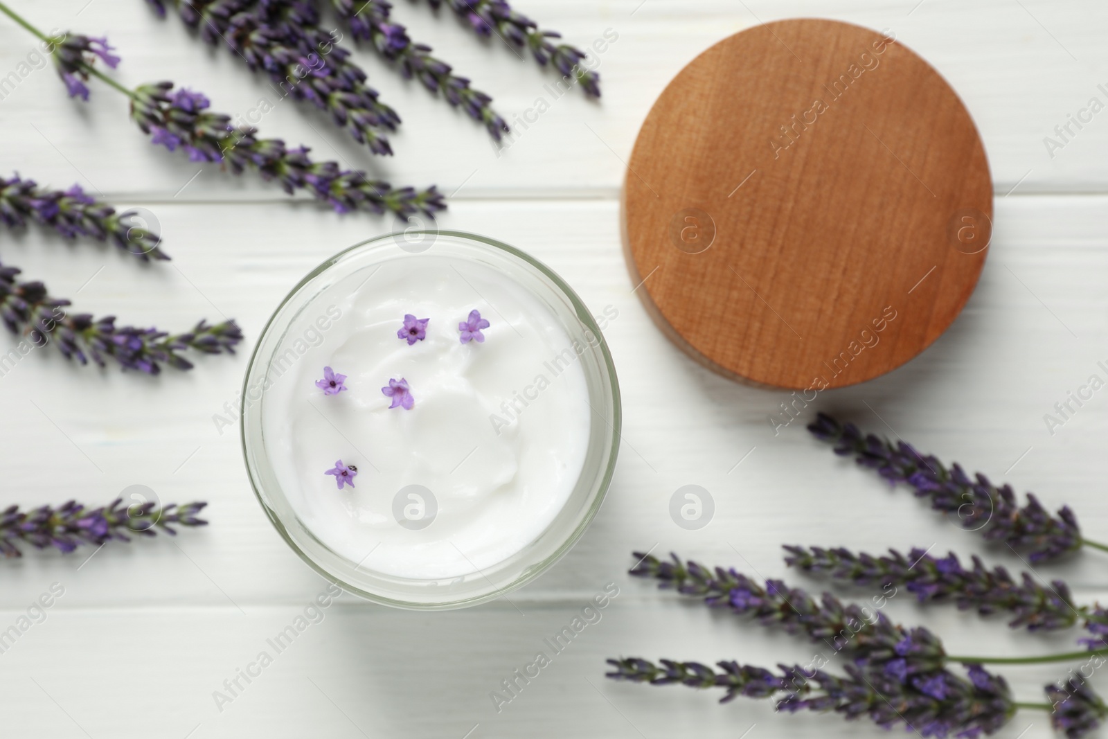 Photo of Jar of face cream and beautiful lavender on white wooden table, flat lay