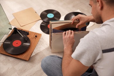 Photo of Man with collection of vinyl records near turntable at home