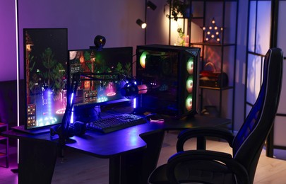 Playing video games. Stylish room interior with modern computer and gaming chair in neon lights