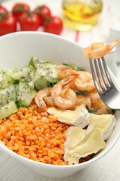Delicious lentil bowl with shrimps, soft cheese and cucumber on white wooden table
