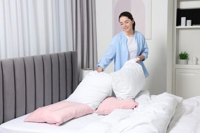 Young woman changing bed linens at home