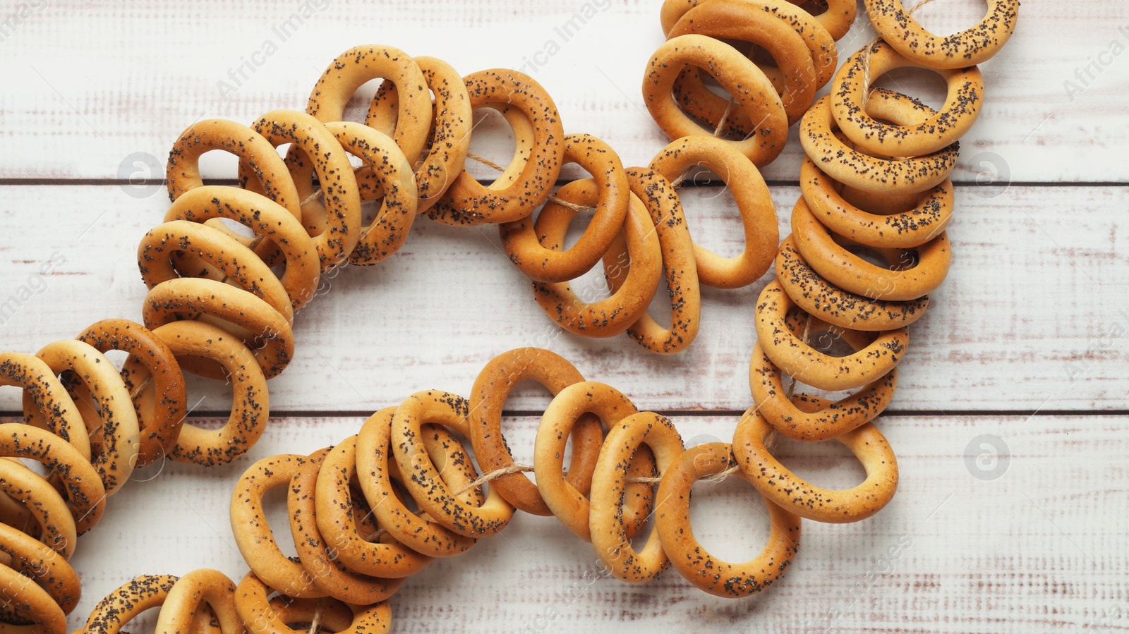 Photo of Bunch of delicious ring shaped Sushki (dry bagels) on white wooden table, top view