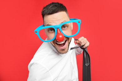 Joyful man with funny glasses on red background. April fool's day