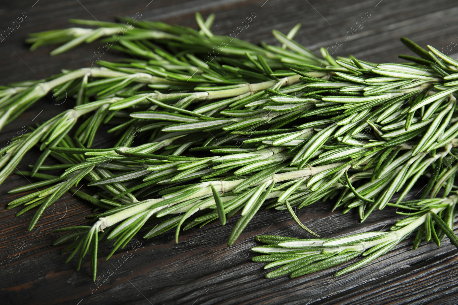 Photo of Fresh rosemary twigs on wooden table, closeup. Aromatic herb