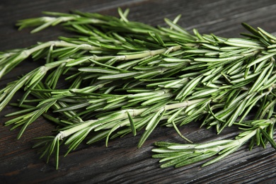 Photo of Fresh rosemary twigs on wooden table, closeup. Aromatic herb