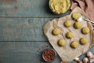 Raw falafel balls and ingredients on light blue wooden table, flat lay. Space for text