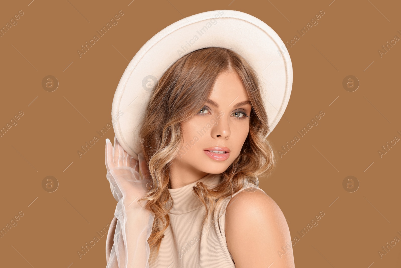 Photo of Portrait of beautiful young woman in stylish hat on light brown background