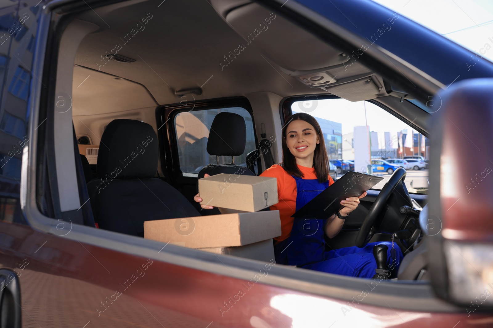 Photo of Courier with clipboard checking packages in car