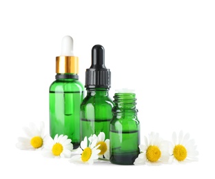 Bottles of herbal essential oil and chamomile flowers isolated on white