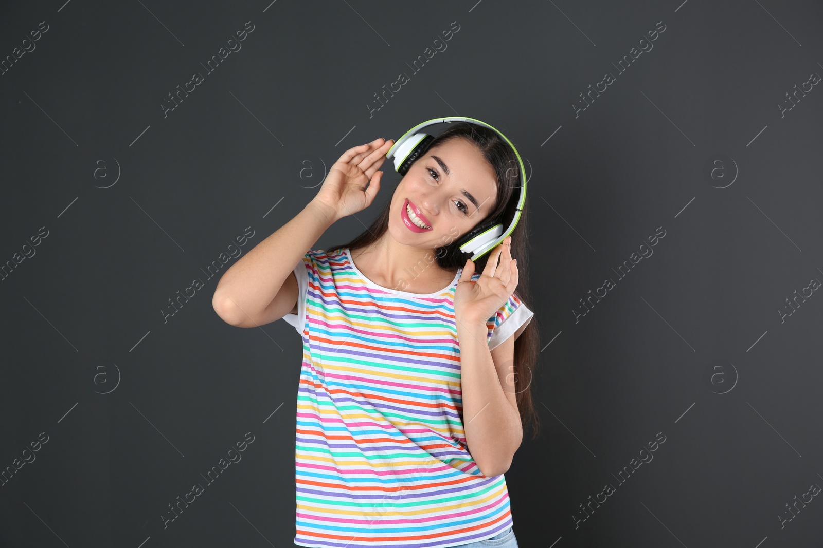 Photo of Beautiful young woman listening to music with headphones on black background