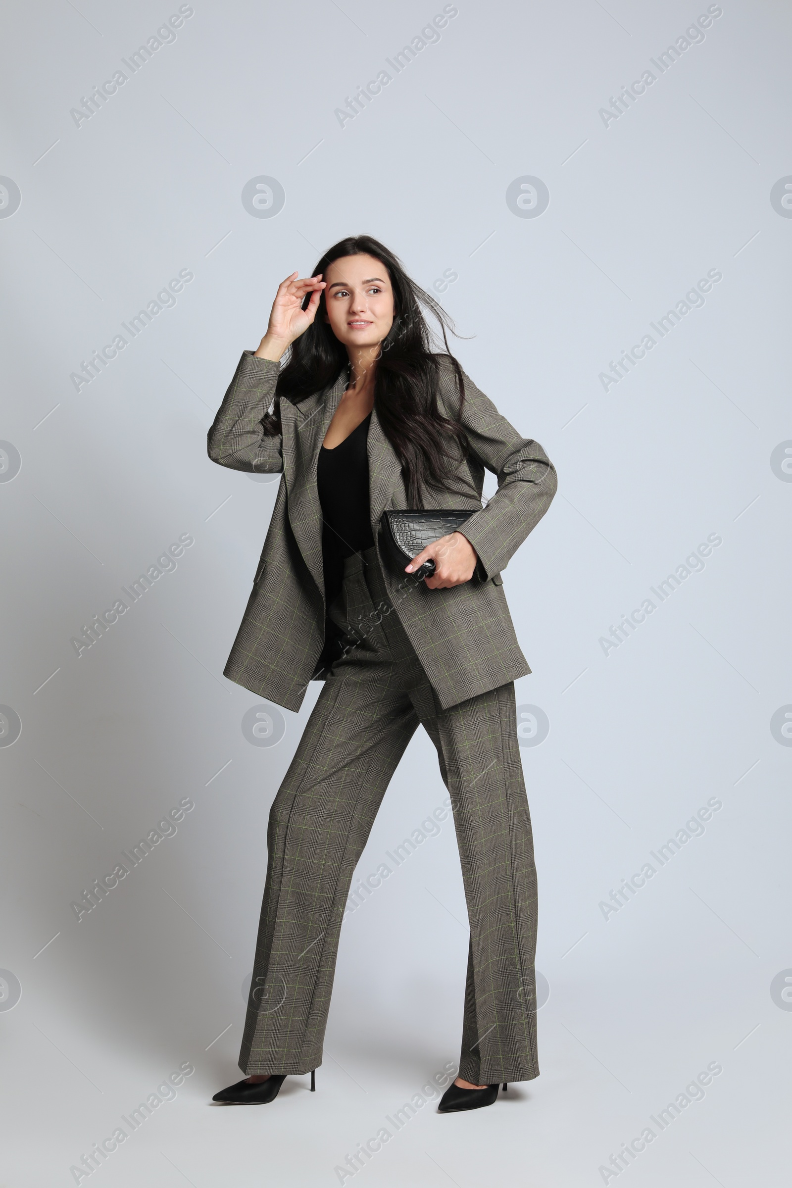 Photo of Full length portrait of beautiful woman with bag in formal suit on light background. Business attire