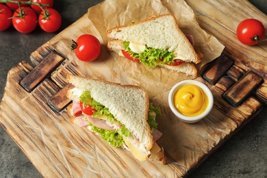 Photo of Tasty toast sandwiches served with mustard on wooden board. Wheat bread