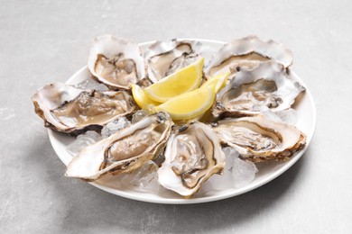 Photo of Delicious fresh oysters with lemon slices on light grey table