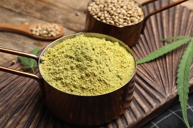 Composition with hemp protein powder and seeds on wooden board, closeup