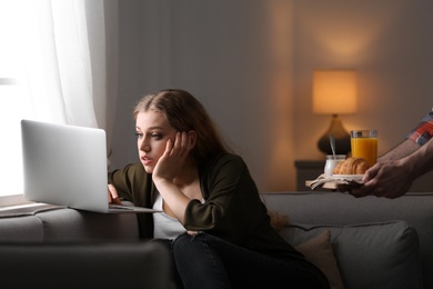 Young woman with laptop ignoring her boyfriend at home. Loneliness concept