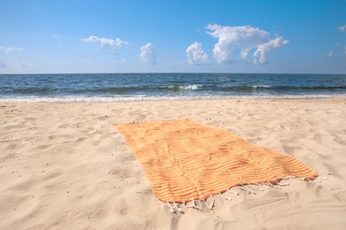 Orange striped beach towel on sandy seashore