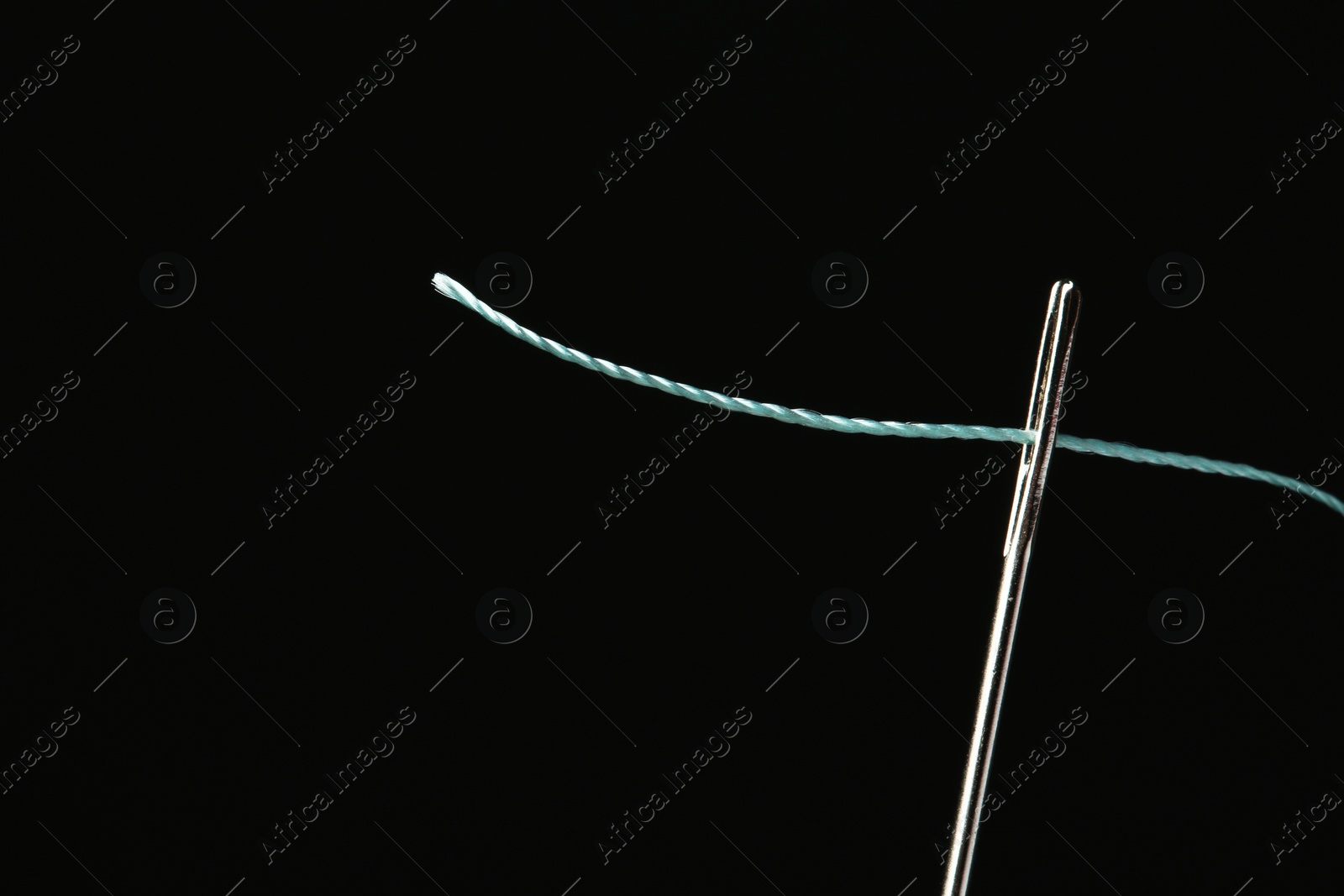Photo of Needle with sewing thread on black background, closeup