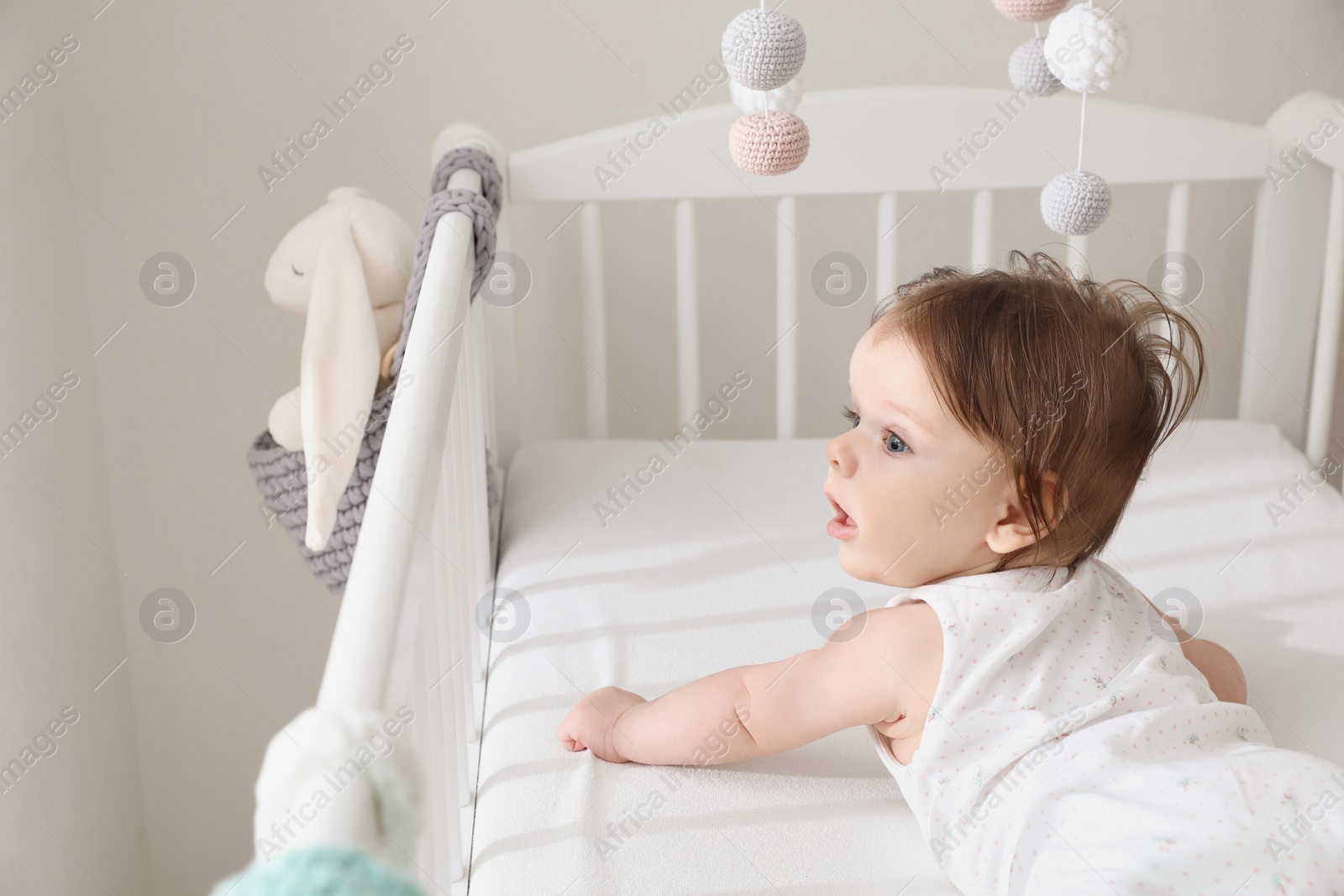 Photo of Cute little baby lying in comfortable crib at home