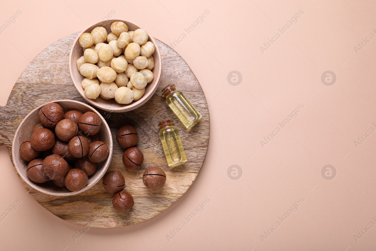 Photo of Delicious organic Macadamia nuts and cosmetic oil on beige background, flat lay. Space for text