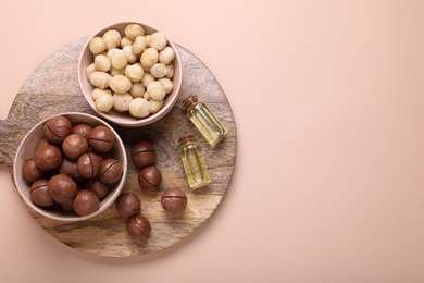 Delicious organic Macadamia nuts and cosmetic oil on beige background, flat lay. Space for text