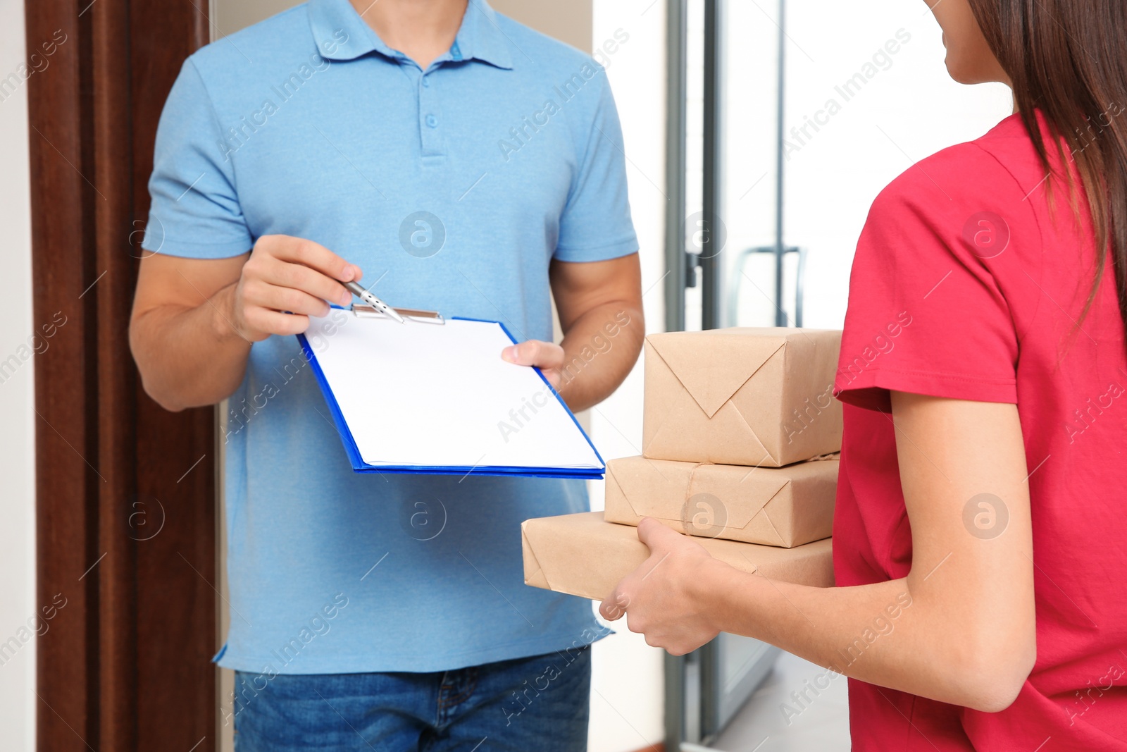 Photo of Woman receiving parcels from delivery service courier indoors, closeup