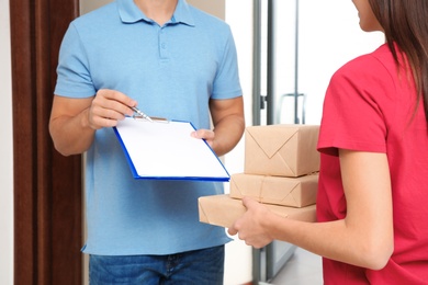 Woman receiving parcels from delivery service courier indoors, closeup