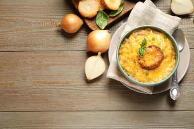 Photo of Tasty homemade French onion soup on wooden table, flat lay. Space for text