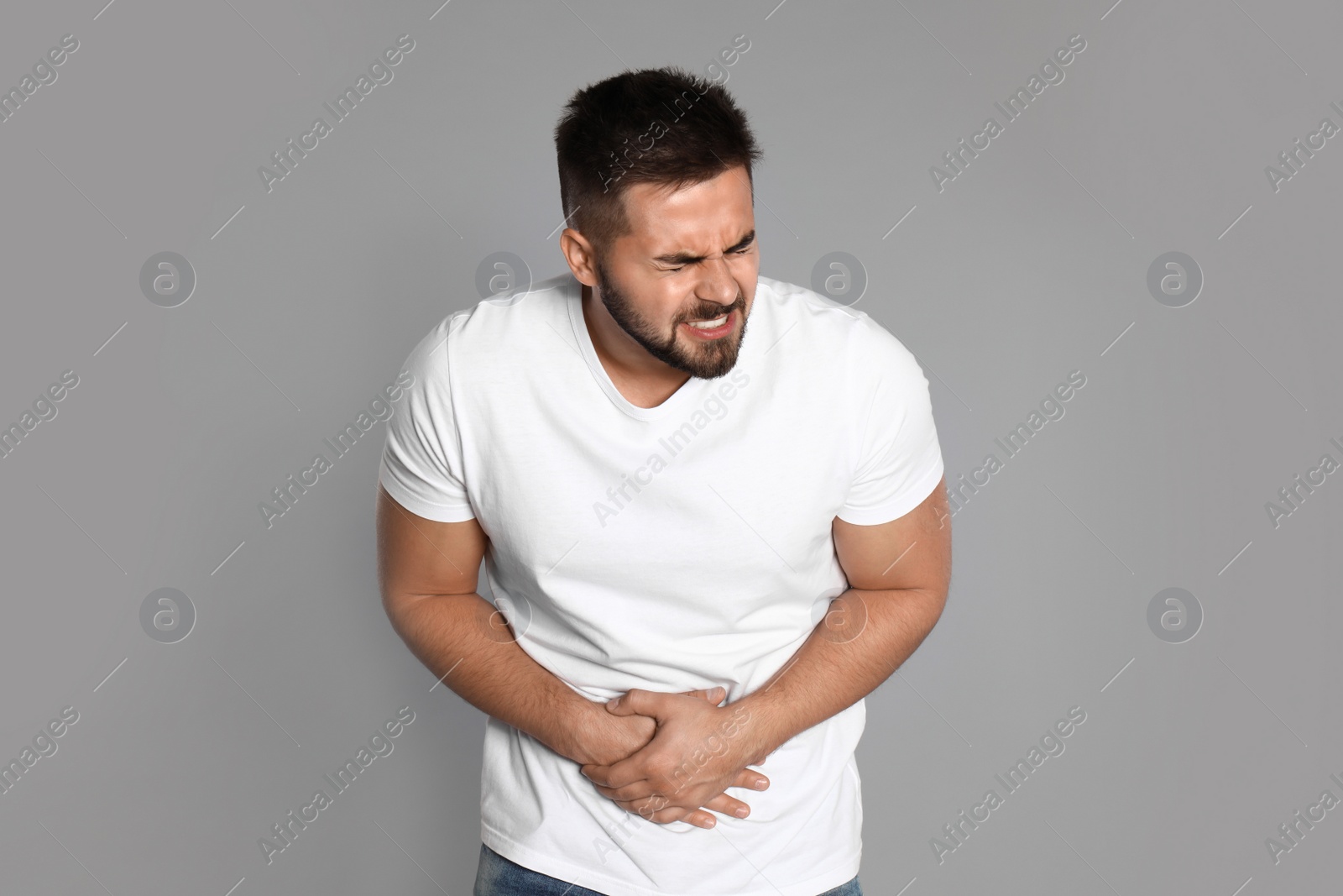 Photo of Man suffering from abdominal pain on light grey background