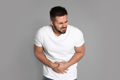 Photo of Man suffering from abdominal pain on light grey background