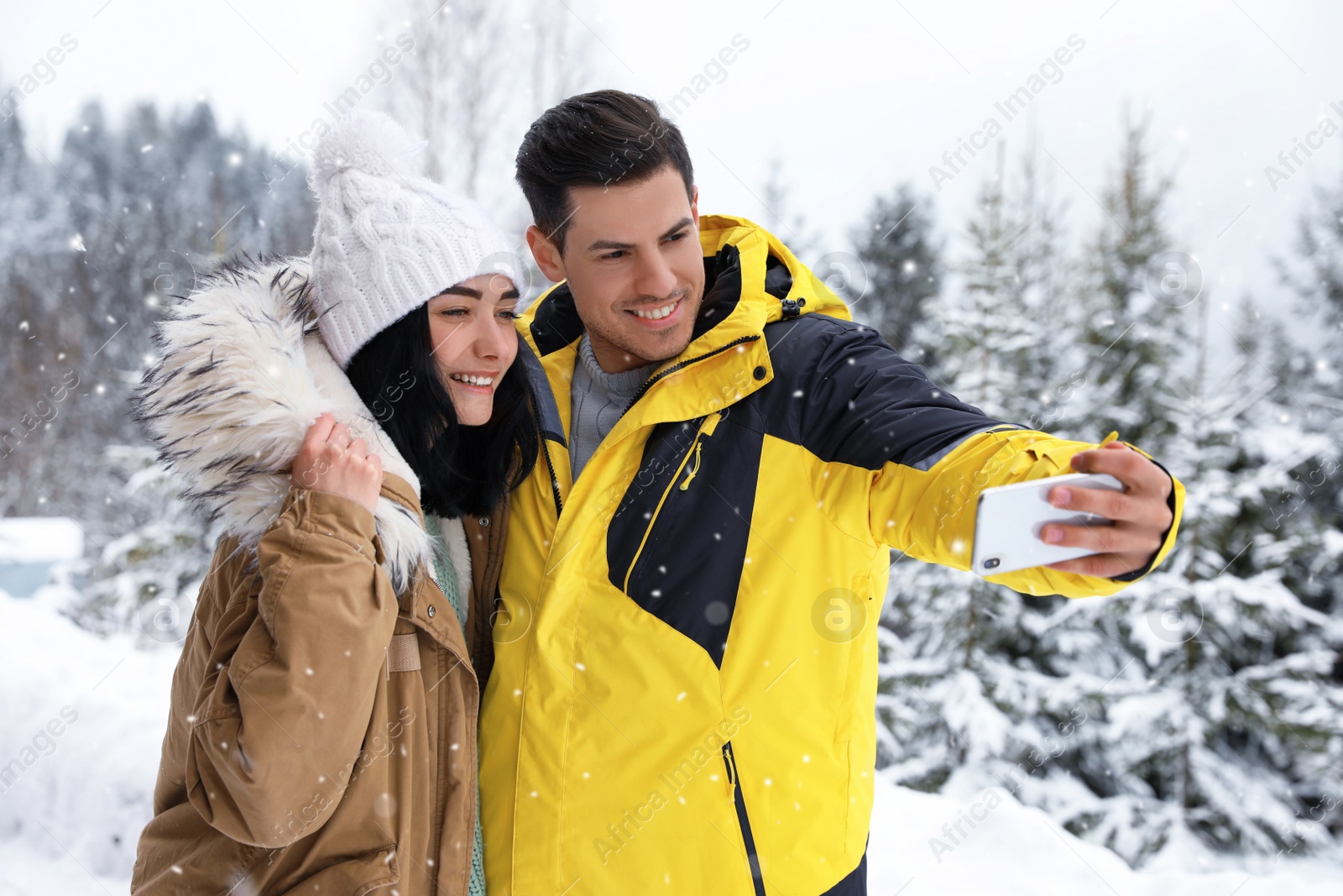 Photo of Happy couple taking selfie near snowy forest. Winter vacation